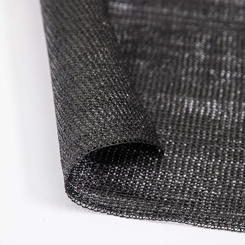 Folded roll of black tape HDPE shade net resting on a green surface