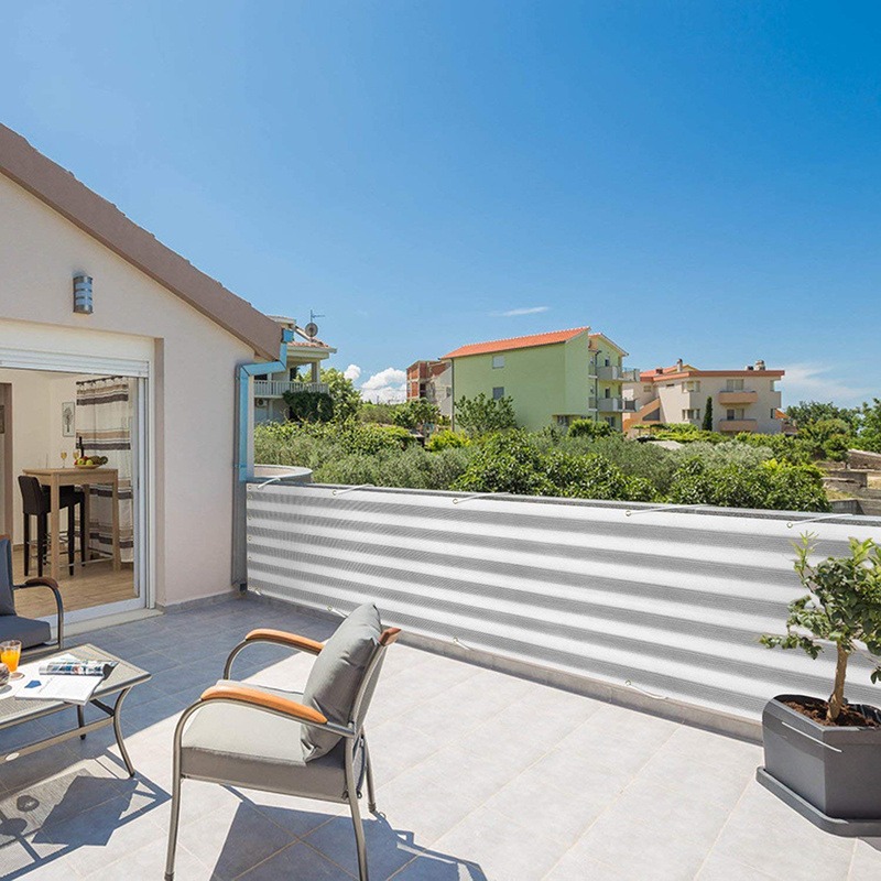 Grey striped HDPE shade net screening a patio in front of a house