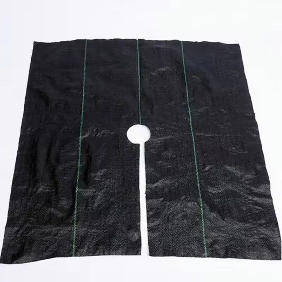 Square perforated weed mat panel with a centre hole and slit on a plain background