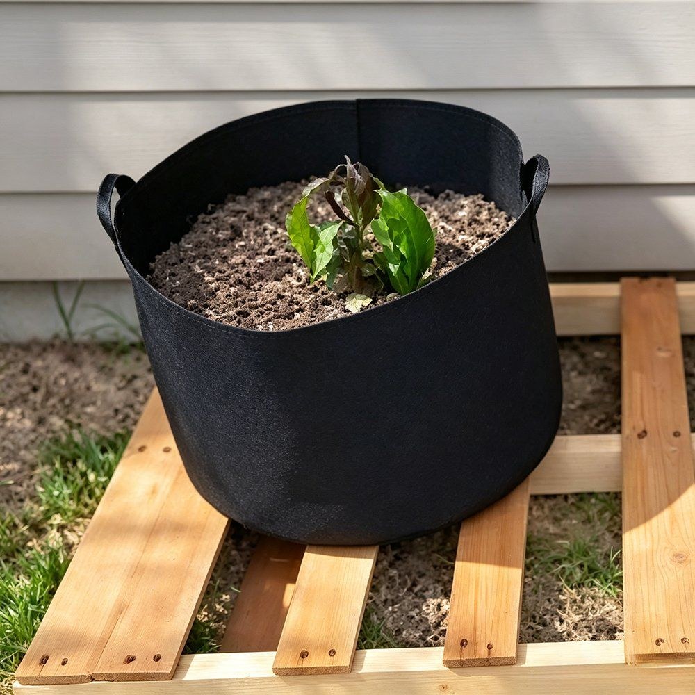 black felt grow bag being filled with compost on a timber pallet