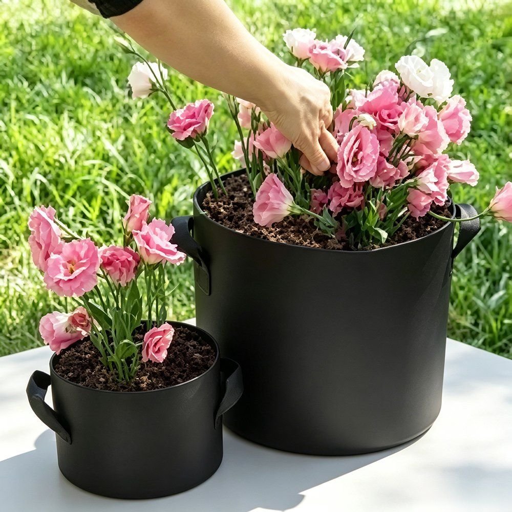 hands planting pink tulips into black felt grow bags in a garden